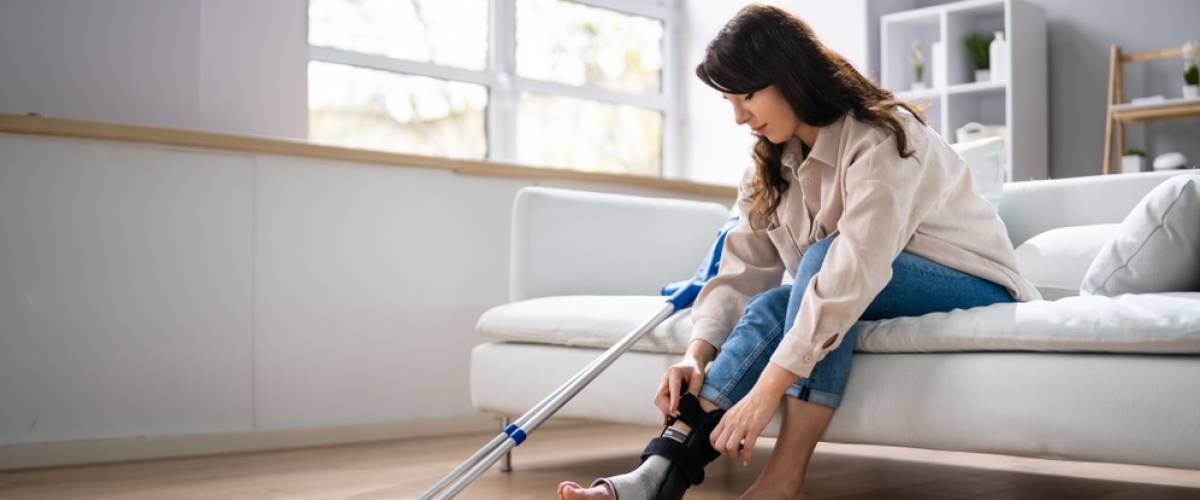 woman with crutches, sitting on couch at home