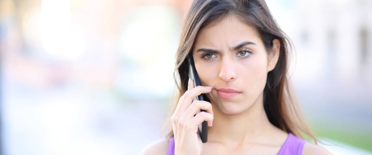 upset young Caucasian woman on phone outside