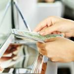 Female hand with money in cash department window. Currency exchange concept