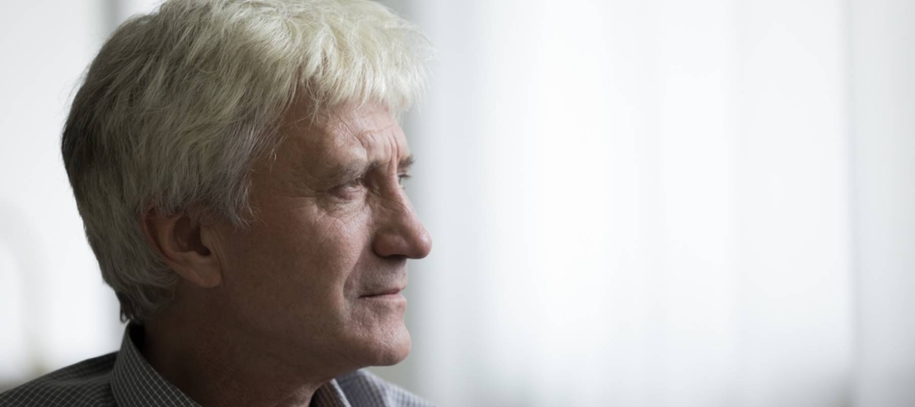 Serious pensive older retired man looking at window