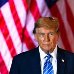 Donald Trump stands in front of an American flag