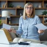 senior woman looking stressed and worried while holding bills