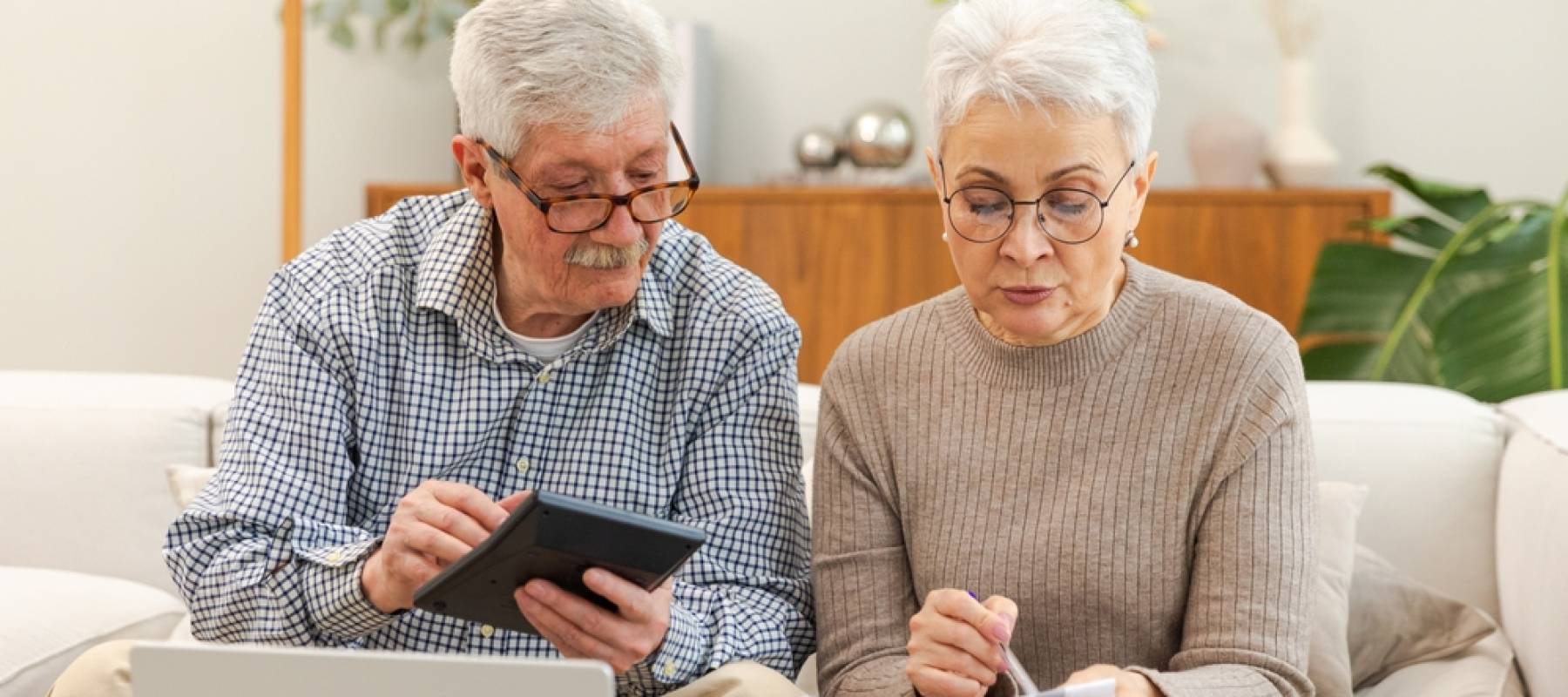 Middle aged senior couple sit with laptop and paper document