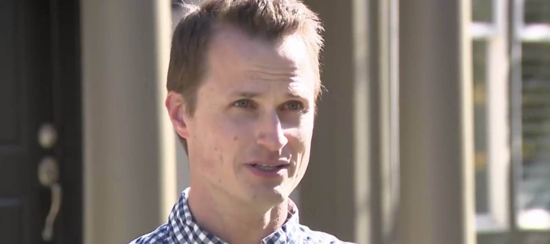 Man stands in front yard, talking directly to camera, upset.