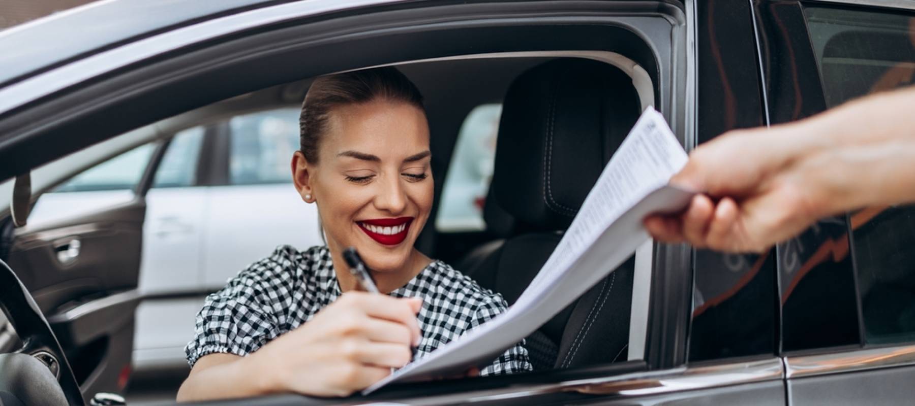 Satisfied and smiled female buyer sitting in her new car.