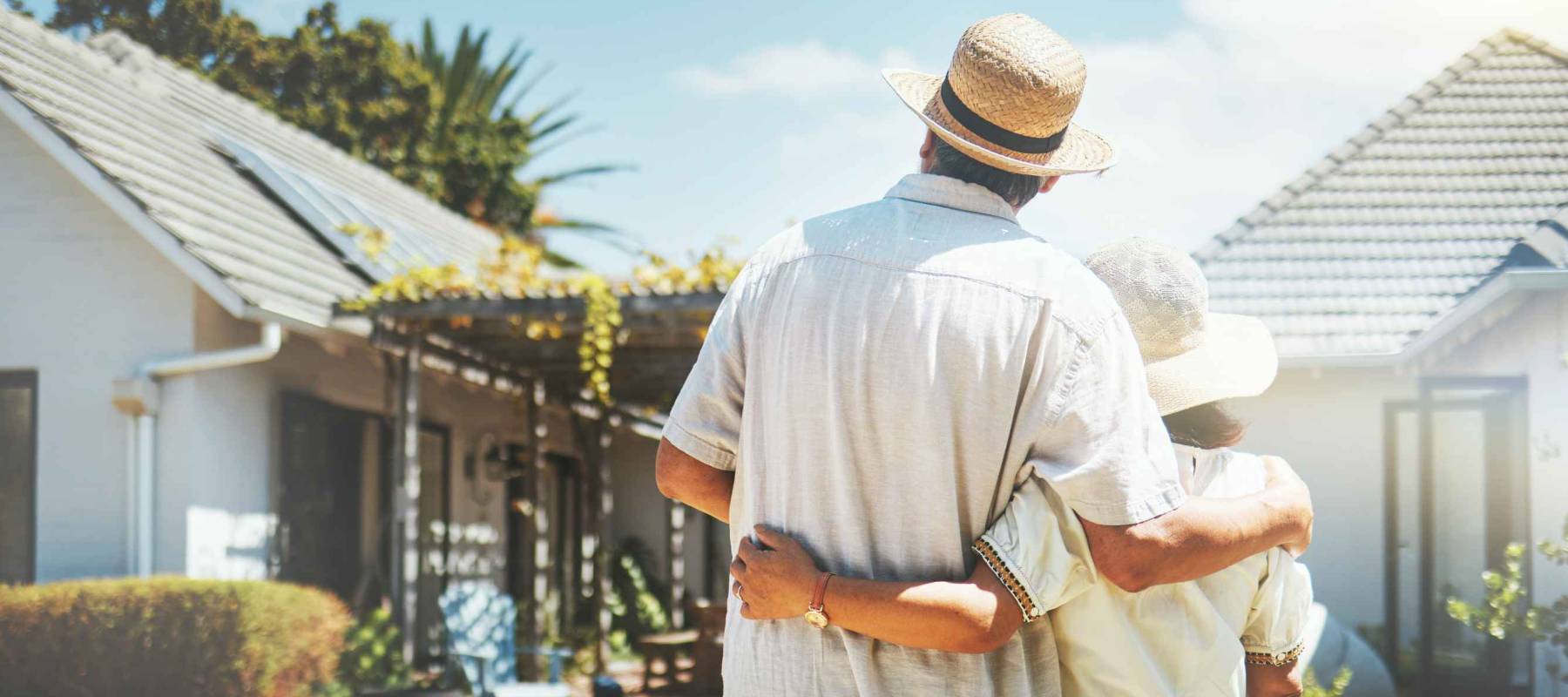 Man, woman embrace in front a house, facing the house.