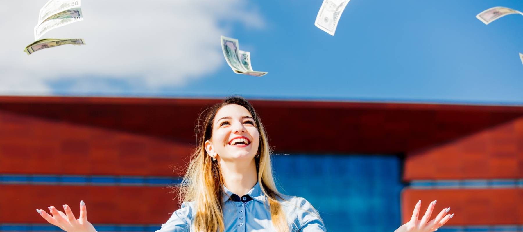 Young woman with hands in the air as paper money falls