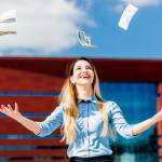Young woman with hands in the air as paper money falls