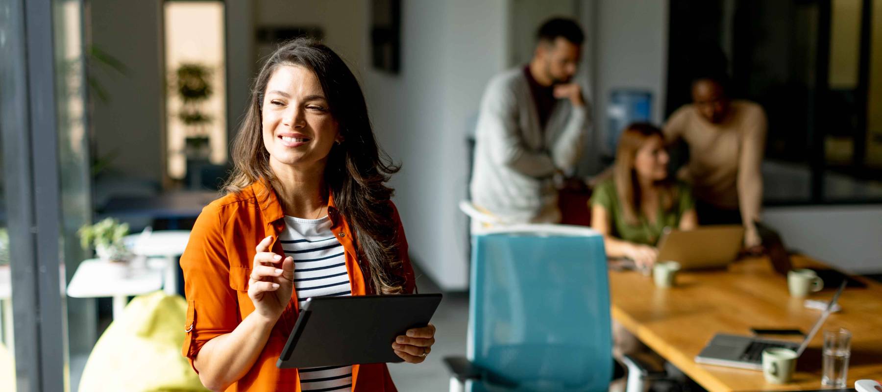 woman standing with digital tablet in front of her team at the modern office