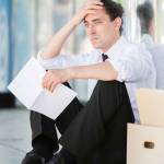Fired frustrated man in suit sitting near office.