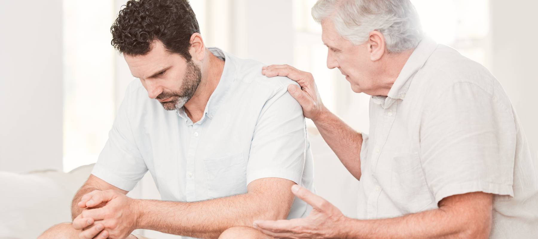 Senior man consoling a middle-aged man