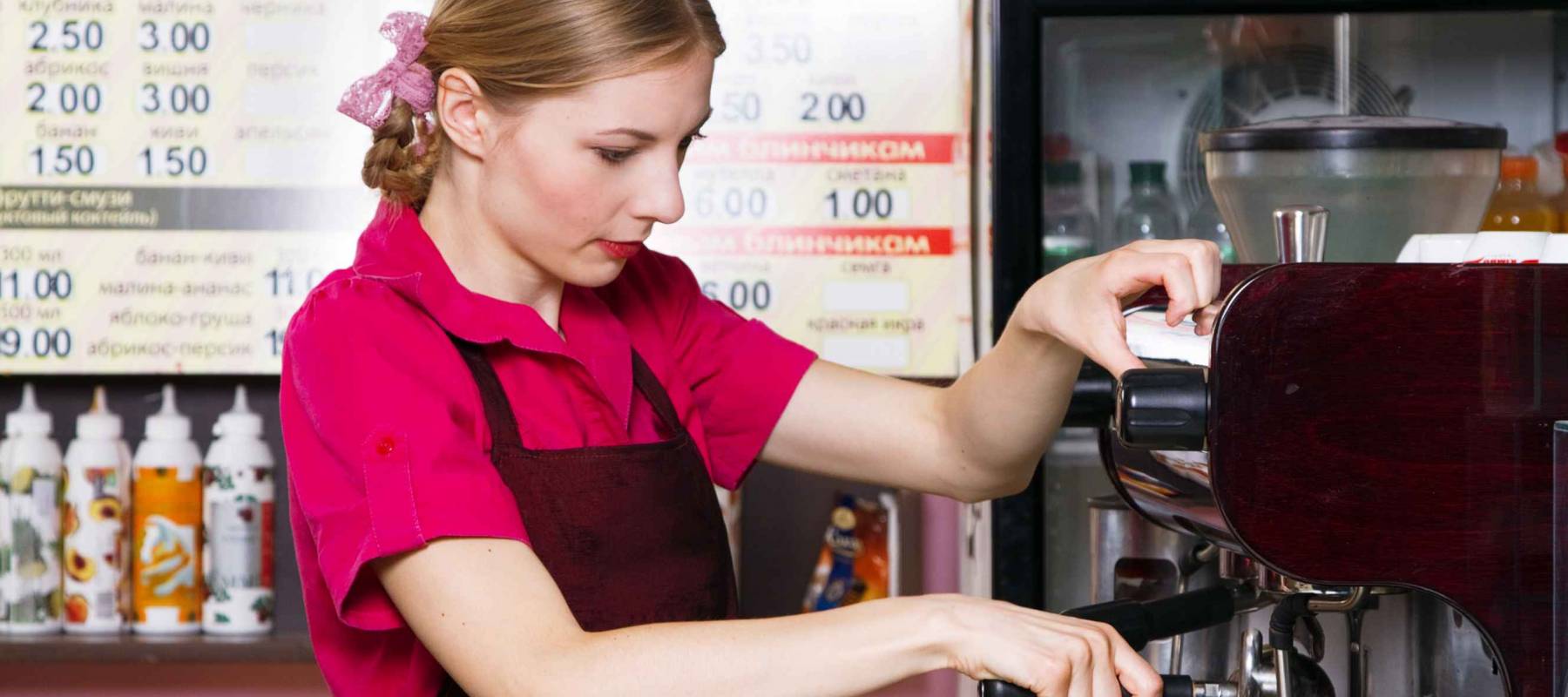 Friendly waitress making coffee at coffee machine