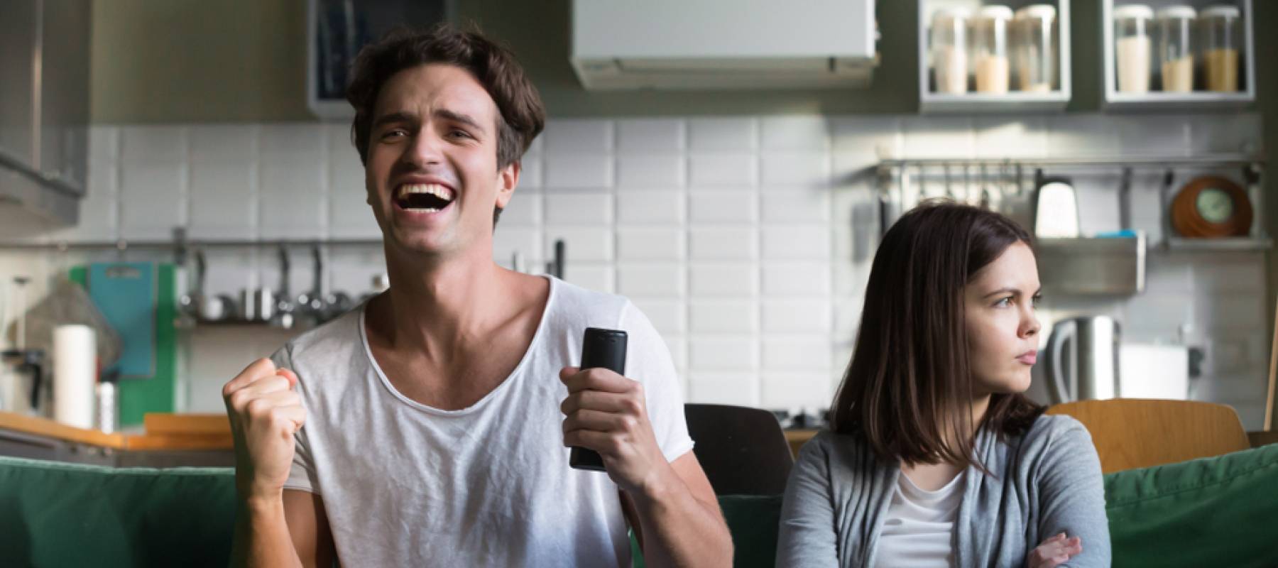 Angry woman sulking while excited football fan watching sport game holding remote