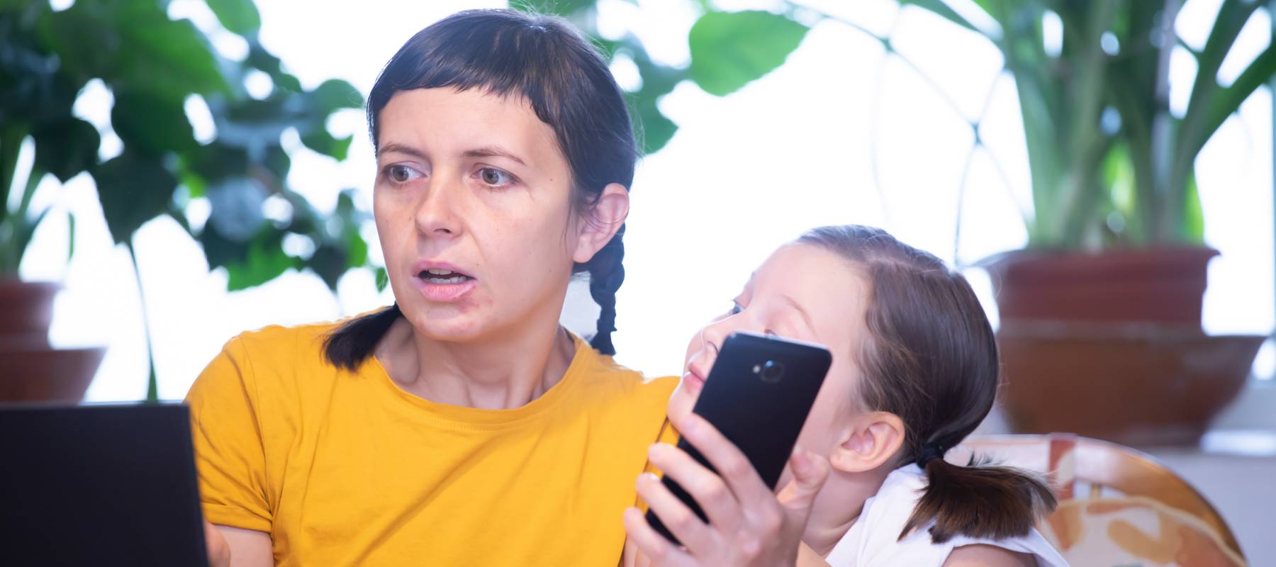 woman surprised at what she's seeing on  computer screen with child on her shoulder