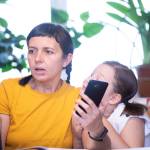 woman surprised at what she's seeing on  computer screen with child on her shoulder