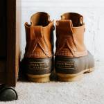 Pair of boots next to a desk on a carpeted floor.