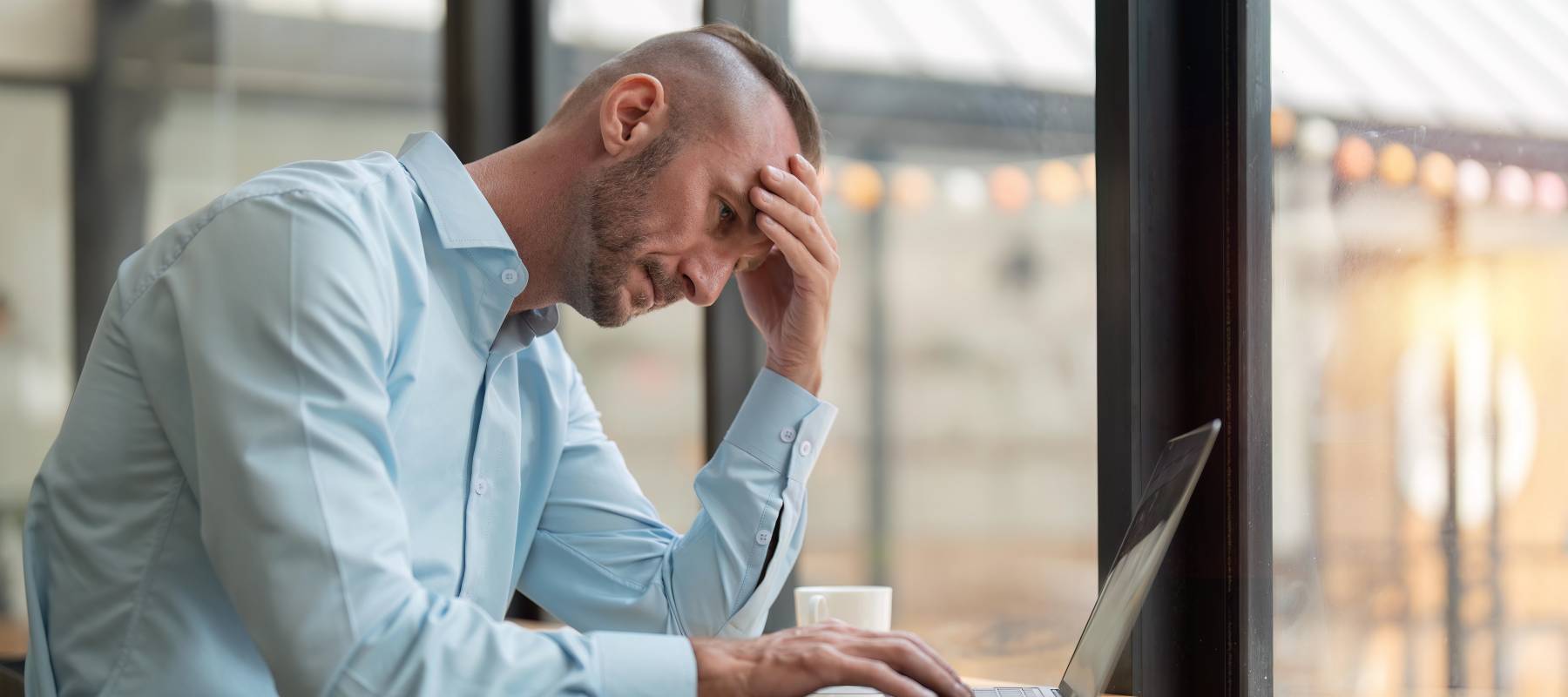 middle aged man working at laptop looking burnt out