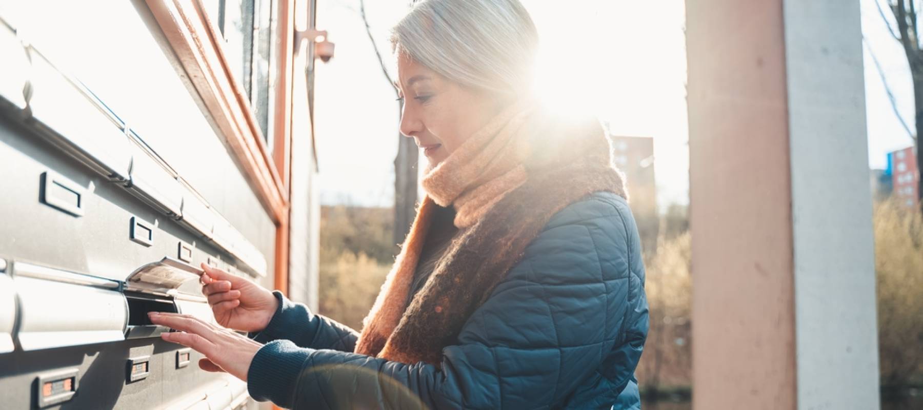Senior woman opens a mailbox.