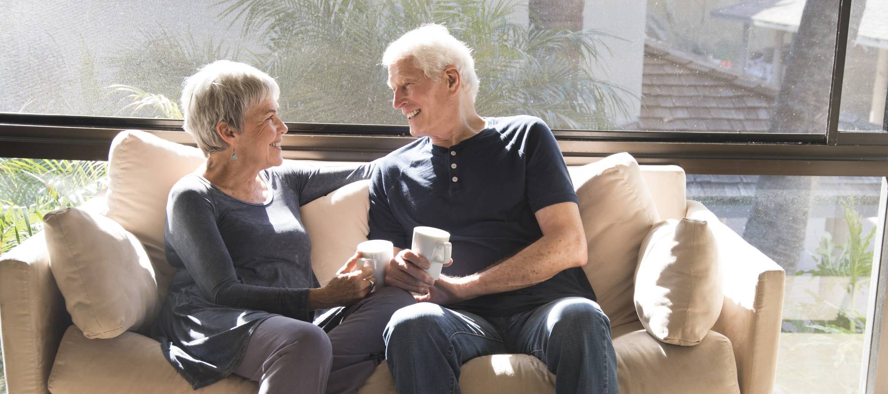 Happy retired couple laughing at home on the couch.