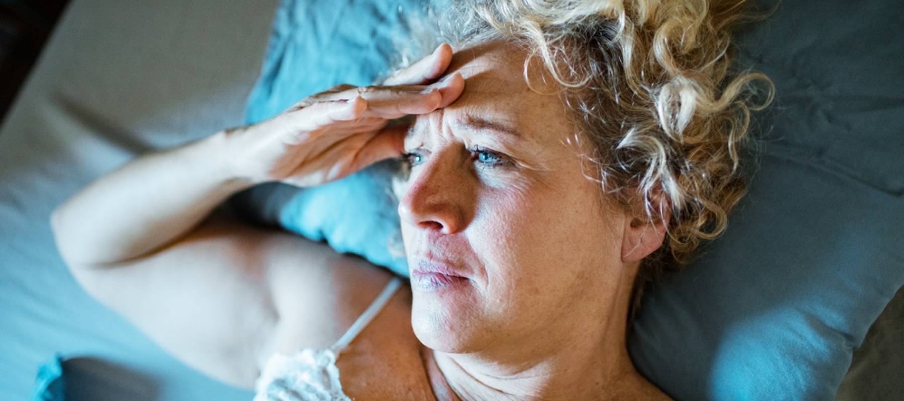 Mature woman lying awake in bed feeling stressed
