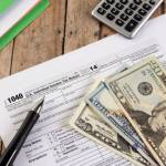 Filing federal taxes for a refund - tax form currency and calculator ona wooden bench