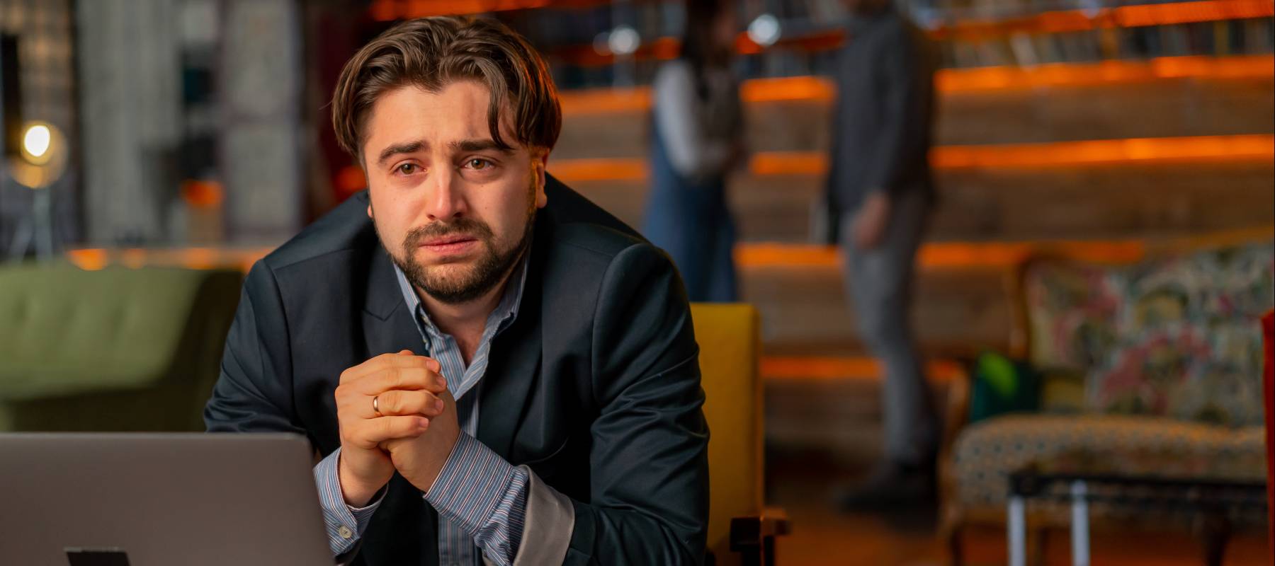 Millennial man worried in a suit in front of a laptop