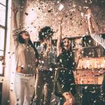 Confetti fun. Group of happy young people throwing confetti and jumping while enjoying home party on the kitchen