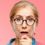 Beautiful senior woman with a goofy, dumb, silly look, feeling shocked and confused at a recent realization, not really understanding an idea.