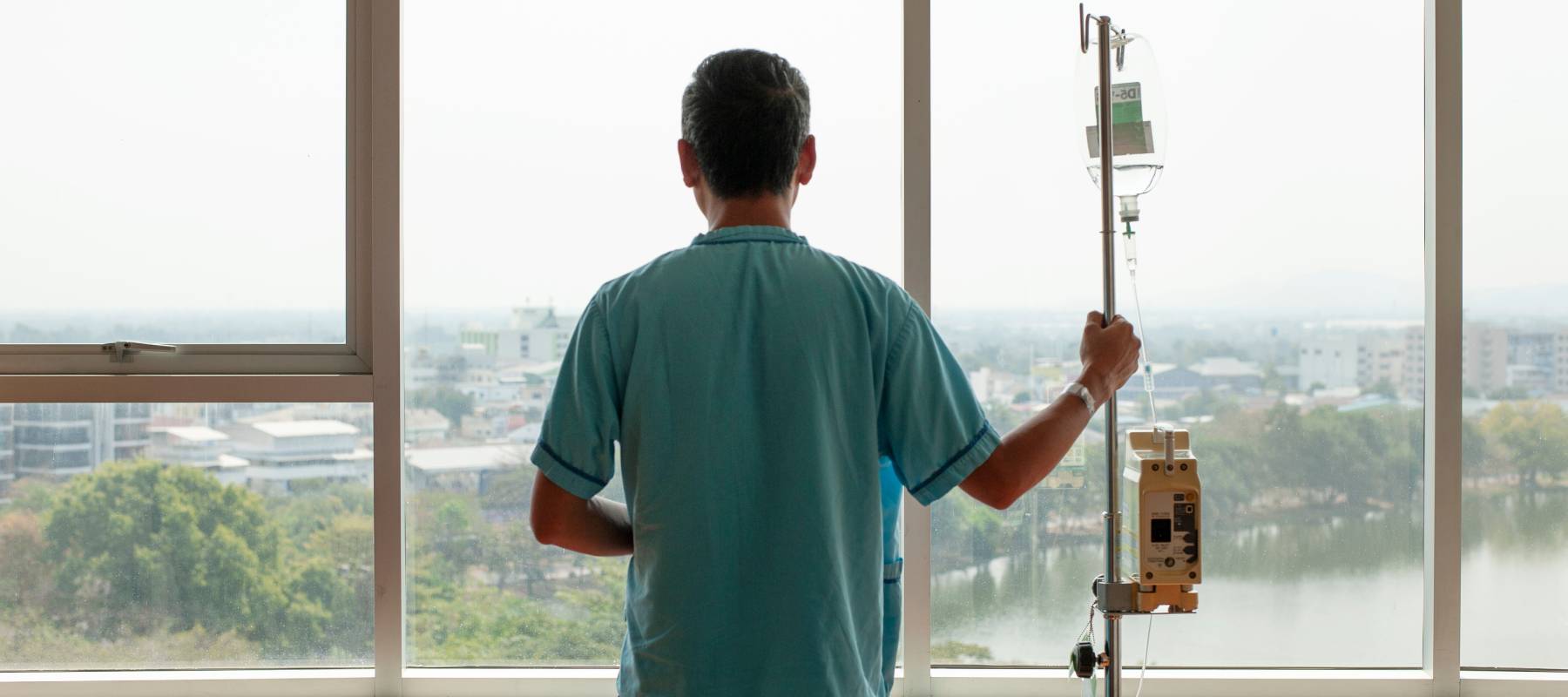 Man undergoing chemotherapy stares out window.