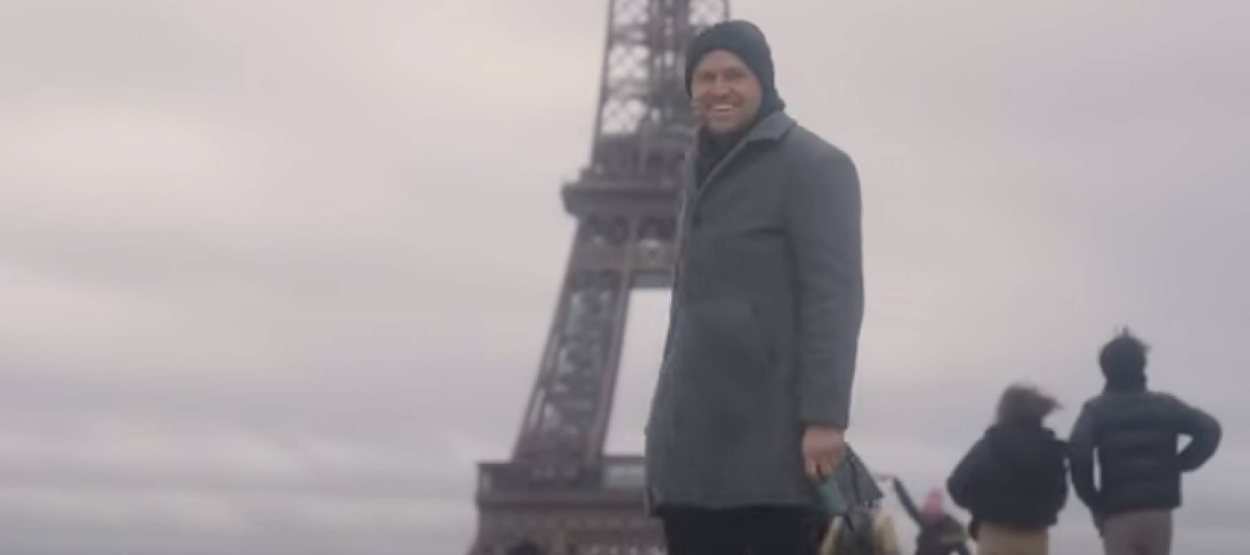 Man walking dog in front of Eiffel Tower.