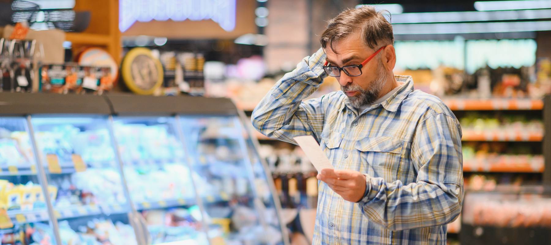 A man is surprised looking at his receipt for groceries.