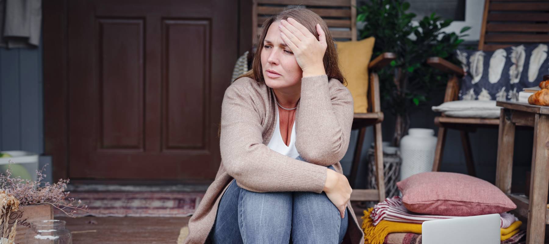 A sad woman sits on her porch.