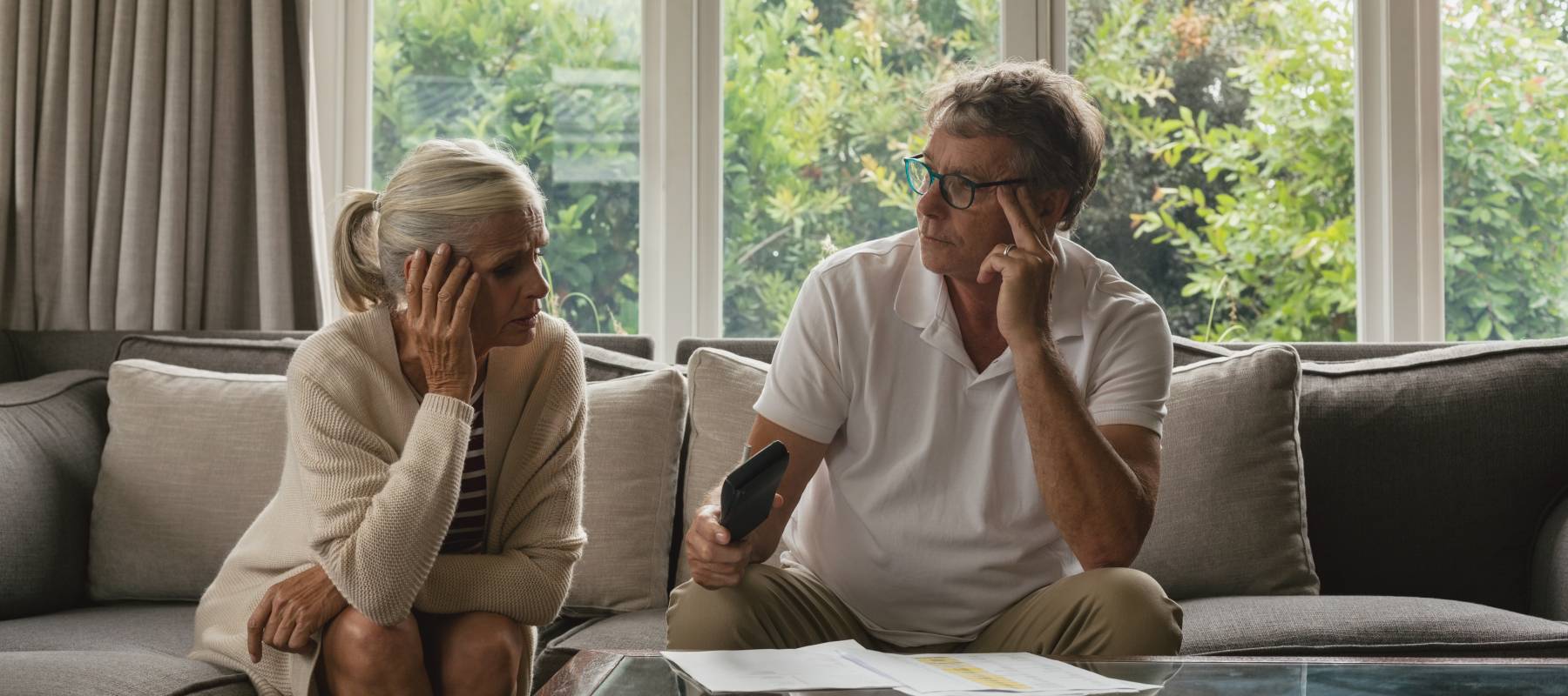 Couple calculating domestic bills on sofa in living room.