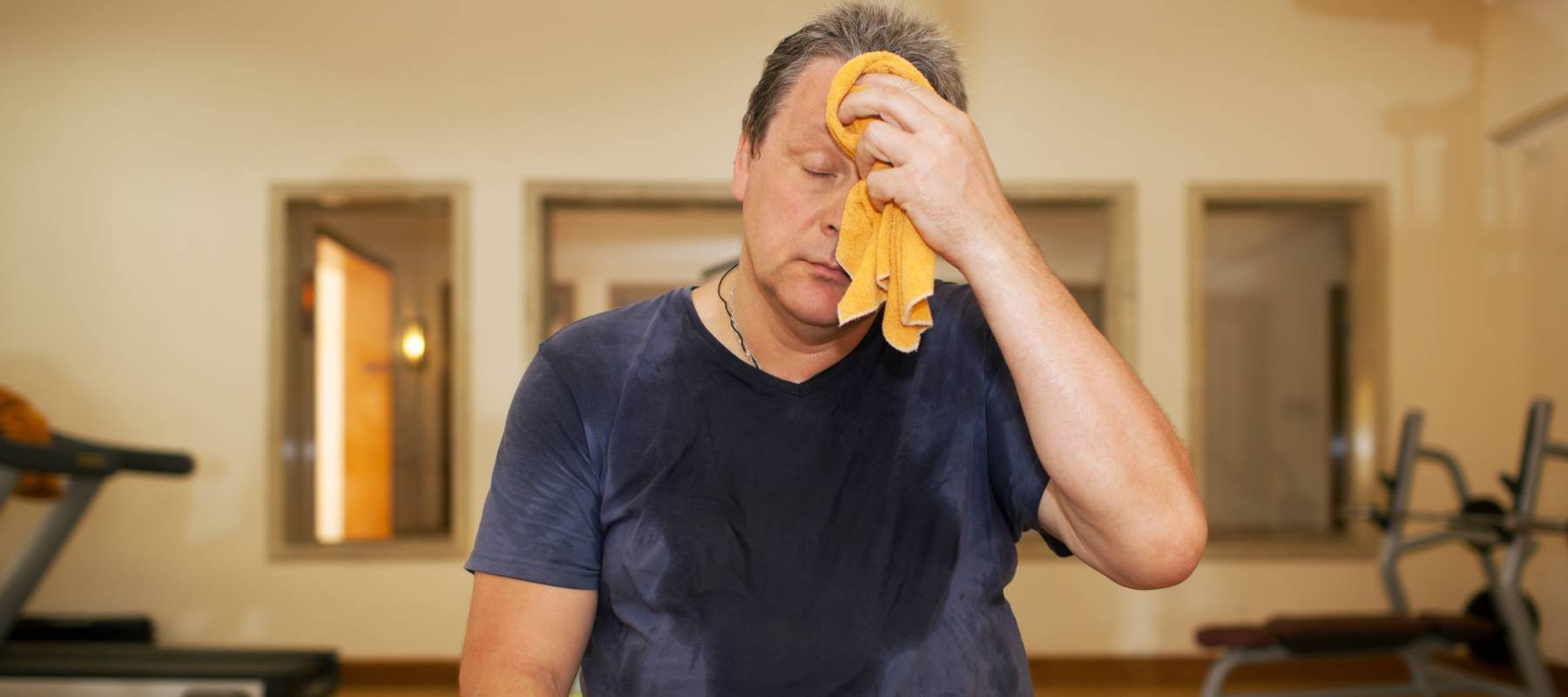 Middle aged man wiping his forehead at the gym