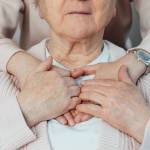 Senior smiling woman feeling young relative's or caregiver supportive touch