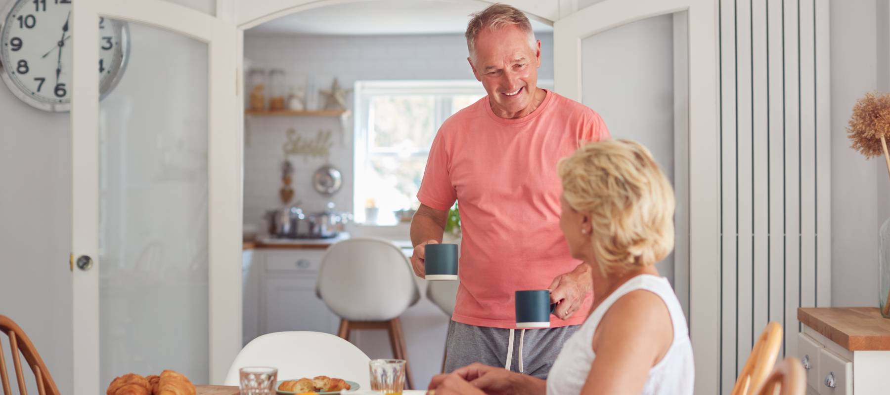 Retired Couple At Home In Kitchen Eating Breakfast Together