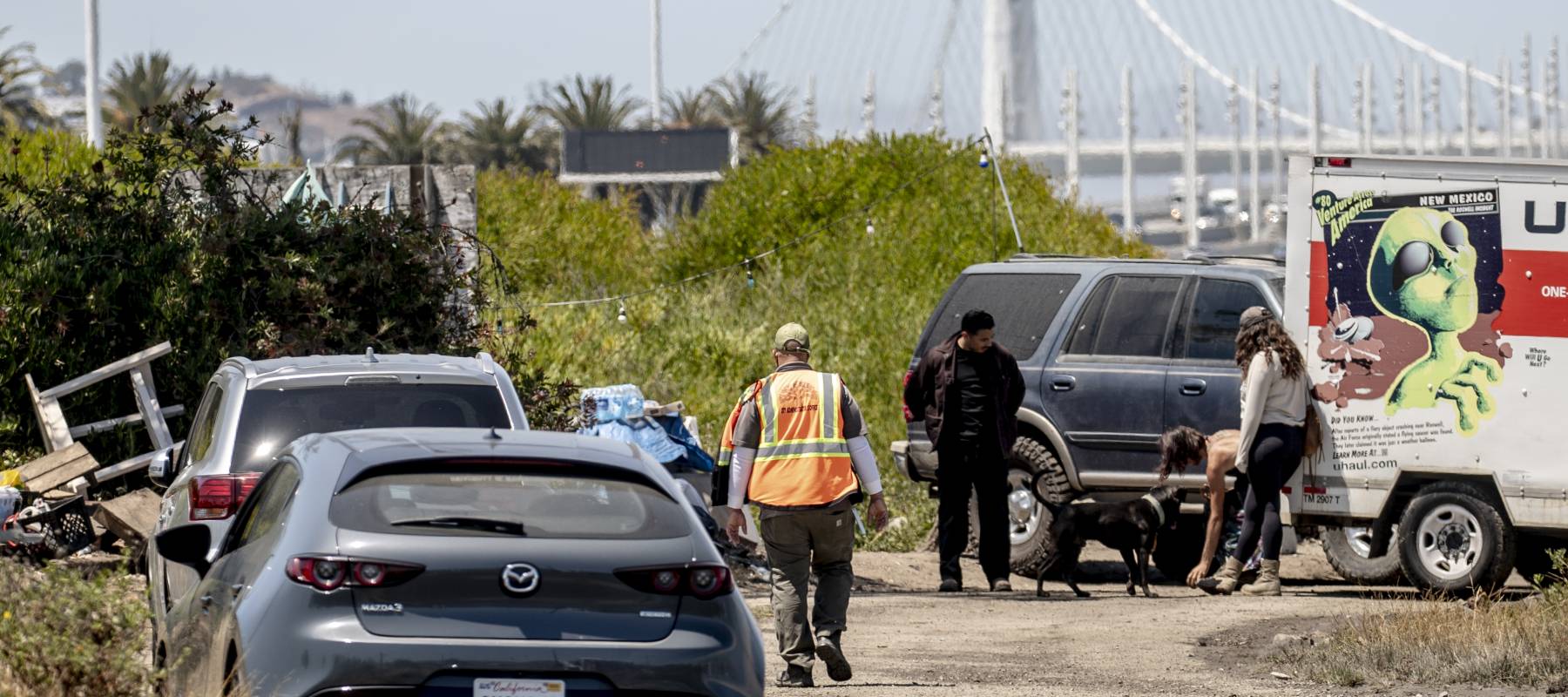 A city worker walks towards a homeless encampment ahead of a scheduled sweep in Oakland, California, July 23, 2024.