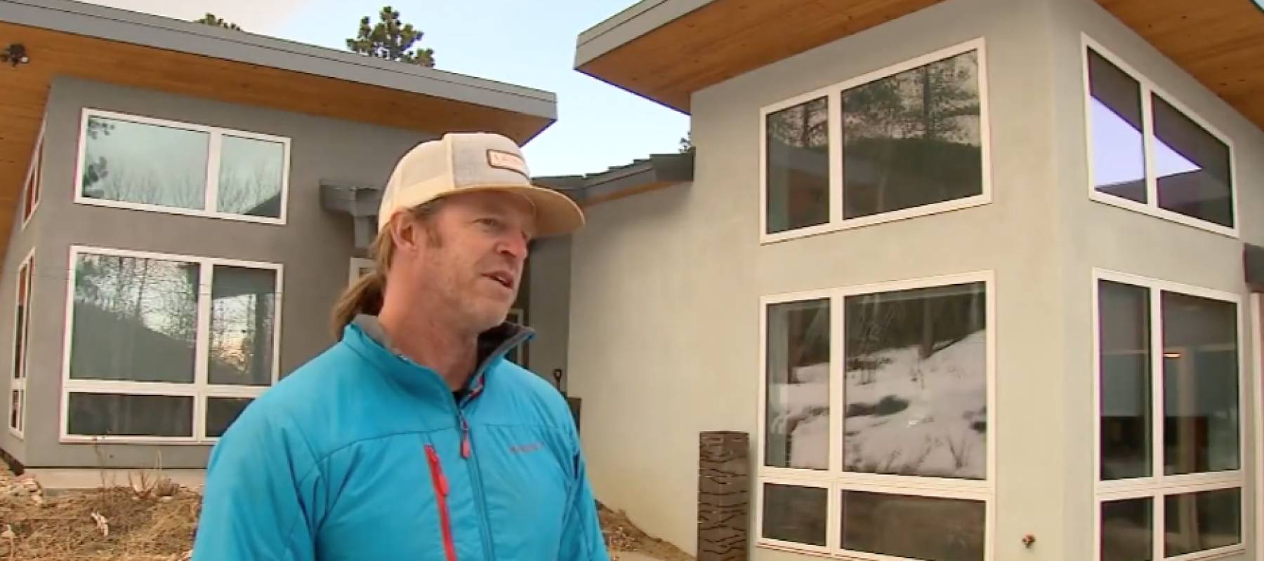 Man stands in front of his house, talking.