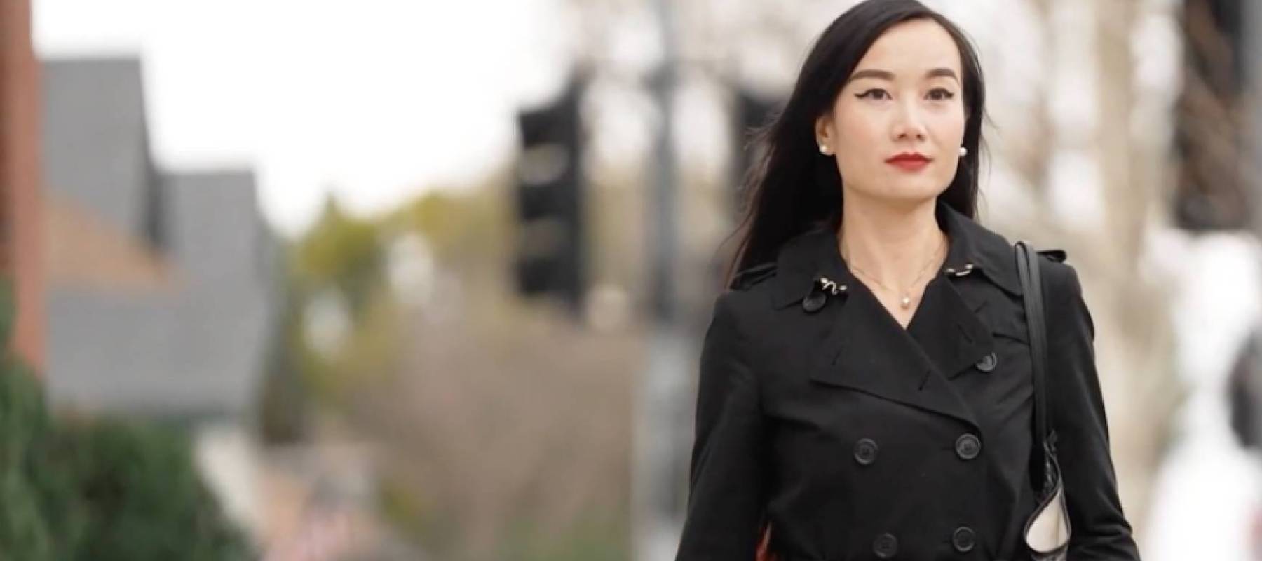 Woman walks down street on overcast day.