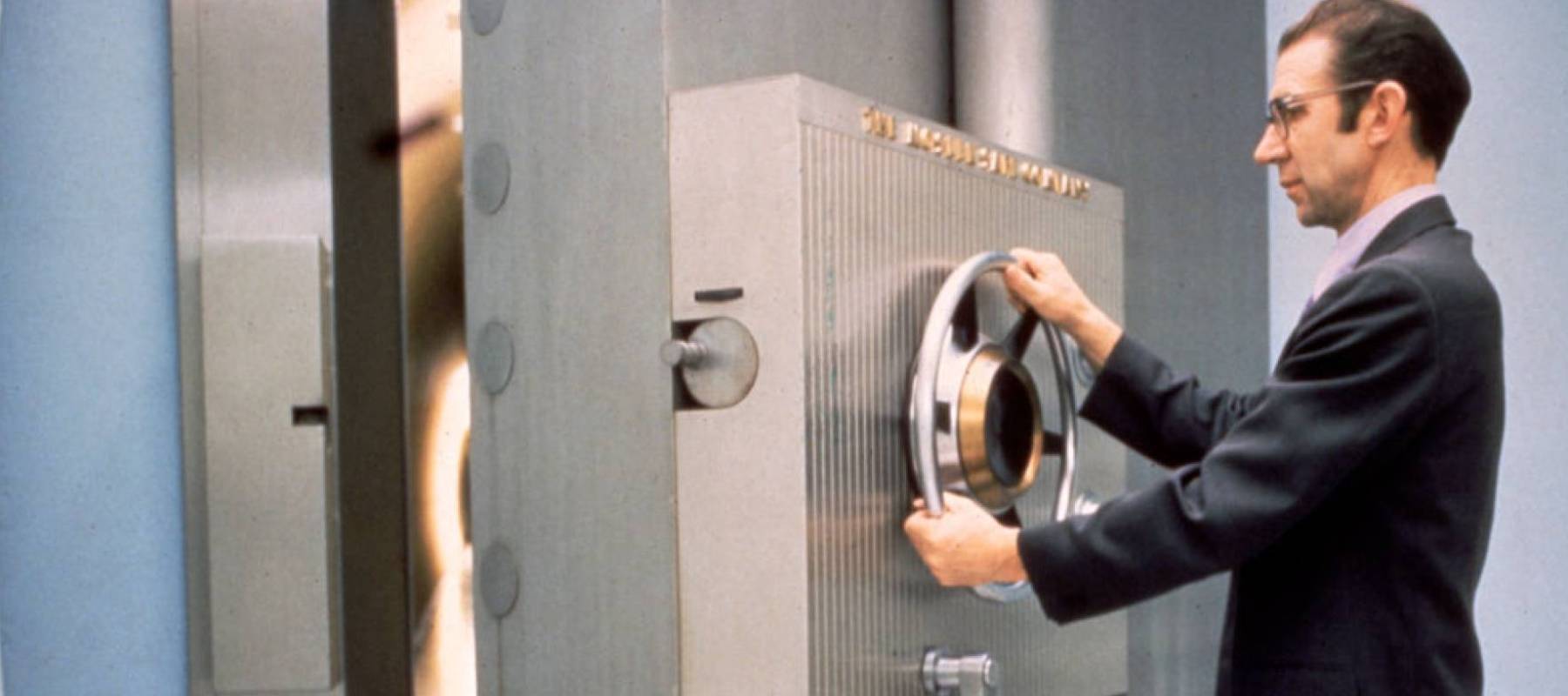 A bank employee closes closes the door of the vault.