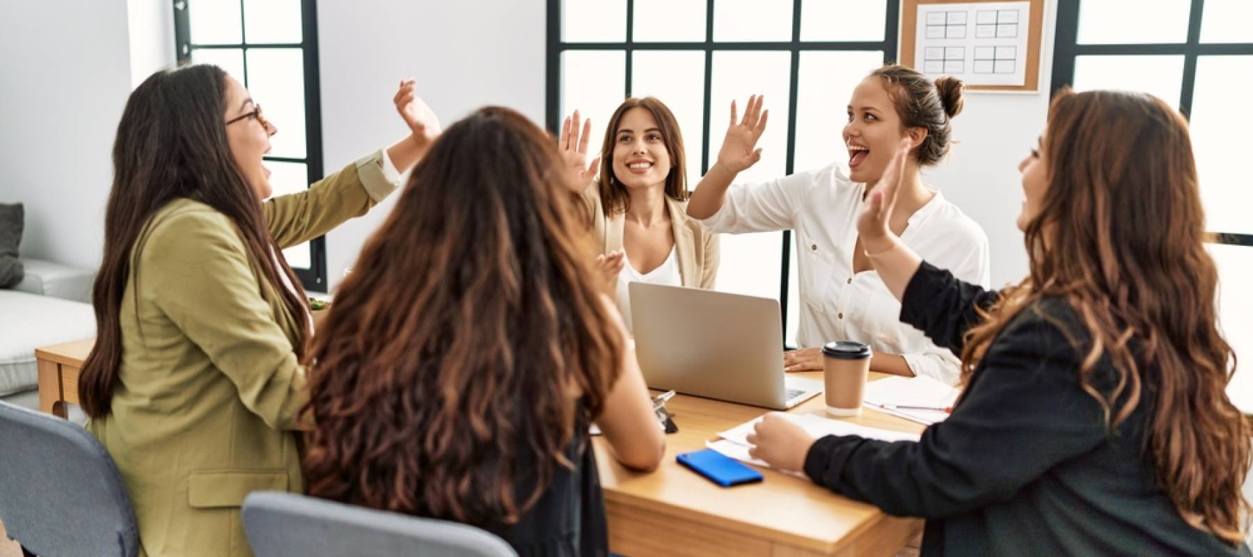 Women high-five each other in a room.