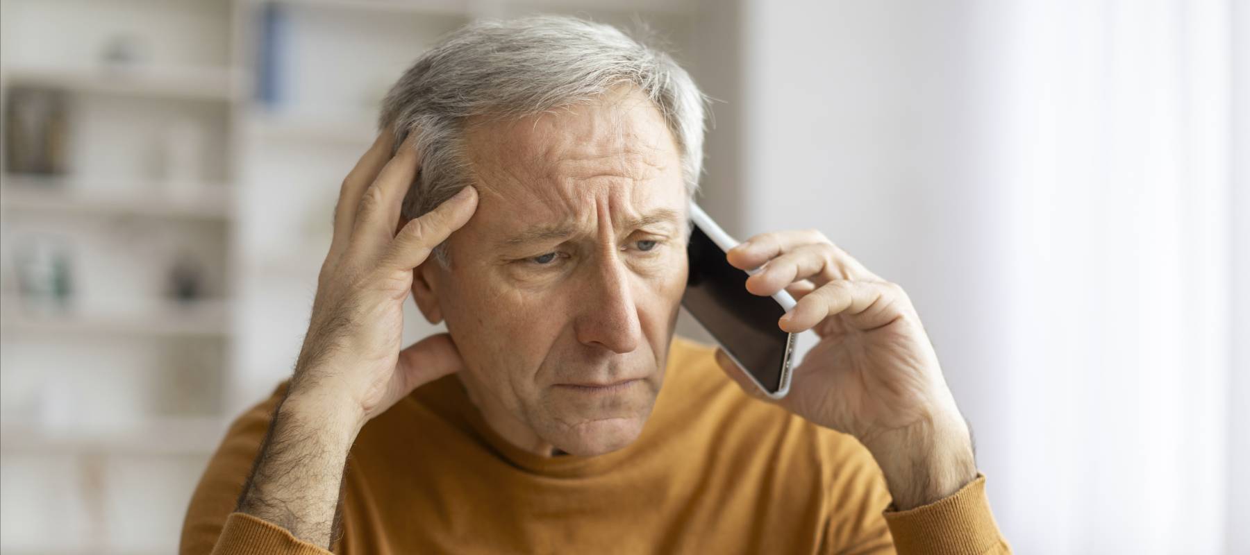 Senior man on hold on his cell phone