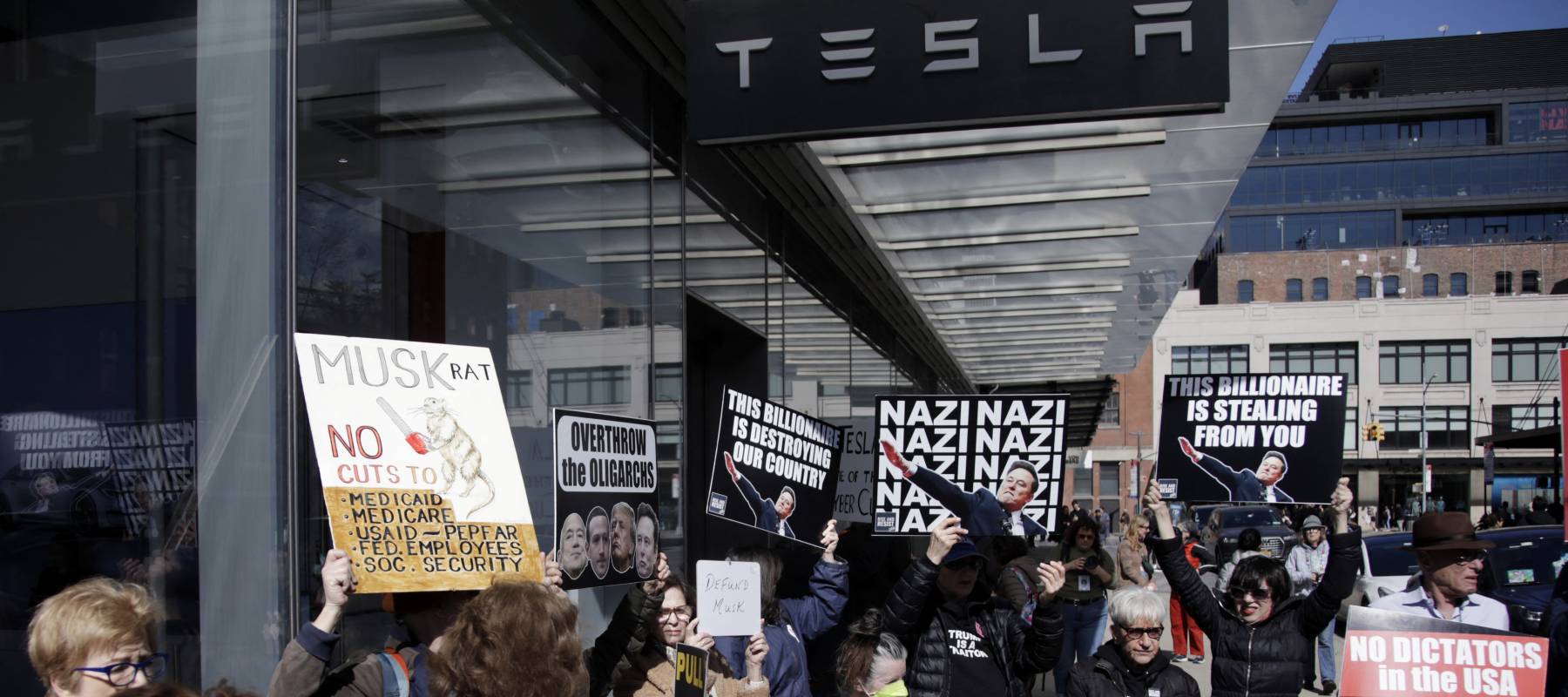 People protesting outside of a Tesla dealership in New York