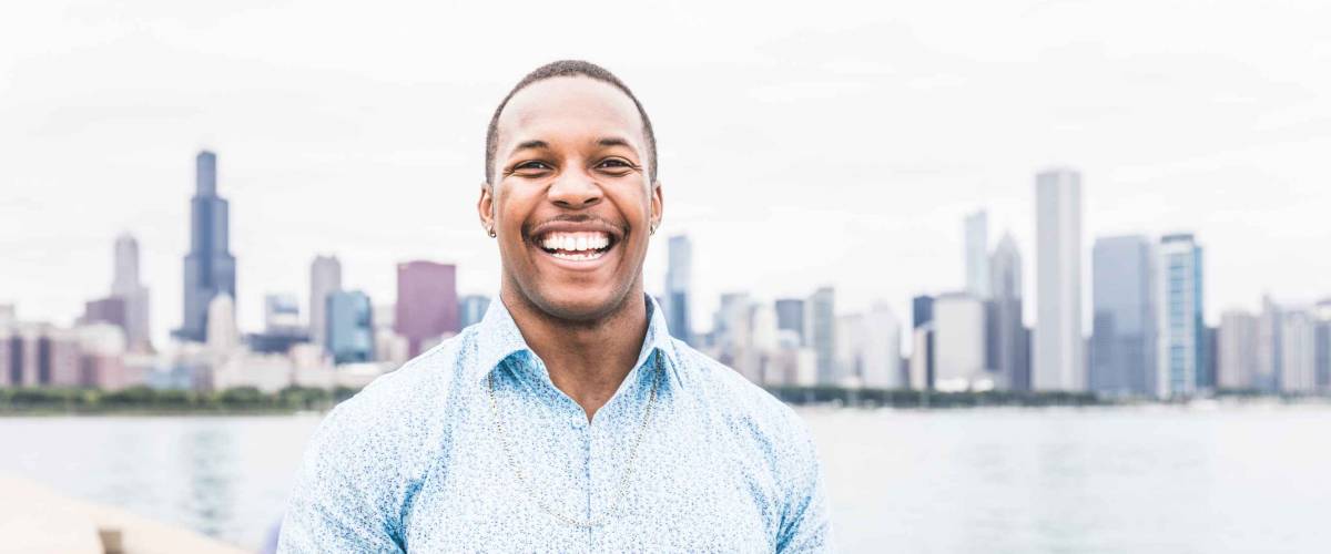 Portrait of happy black man laughing out loud in Chicago. Young man looking at camera with Chicago skyline on background. Happiness and lifestyle concepts.
