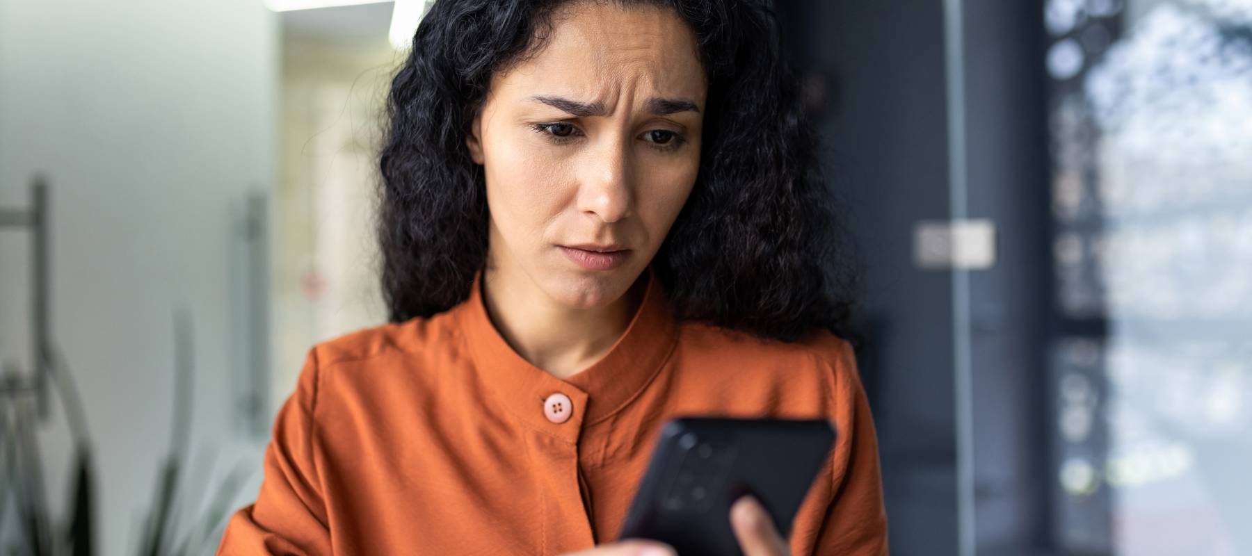 Young woman looking at cell phone worried
