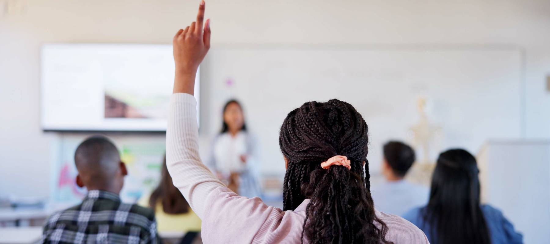 High school student holding up her hand in class