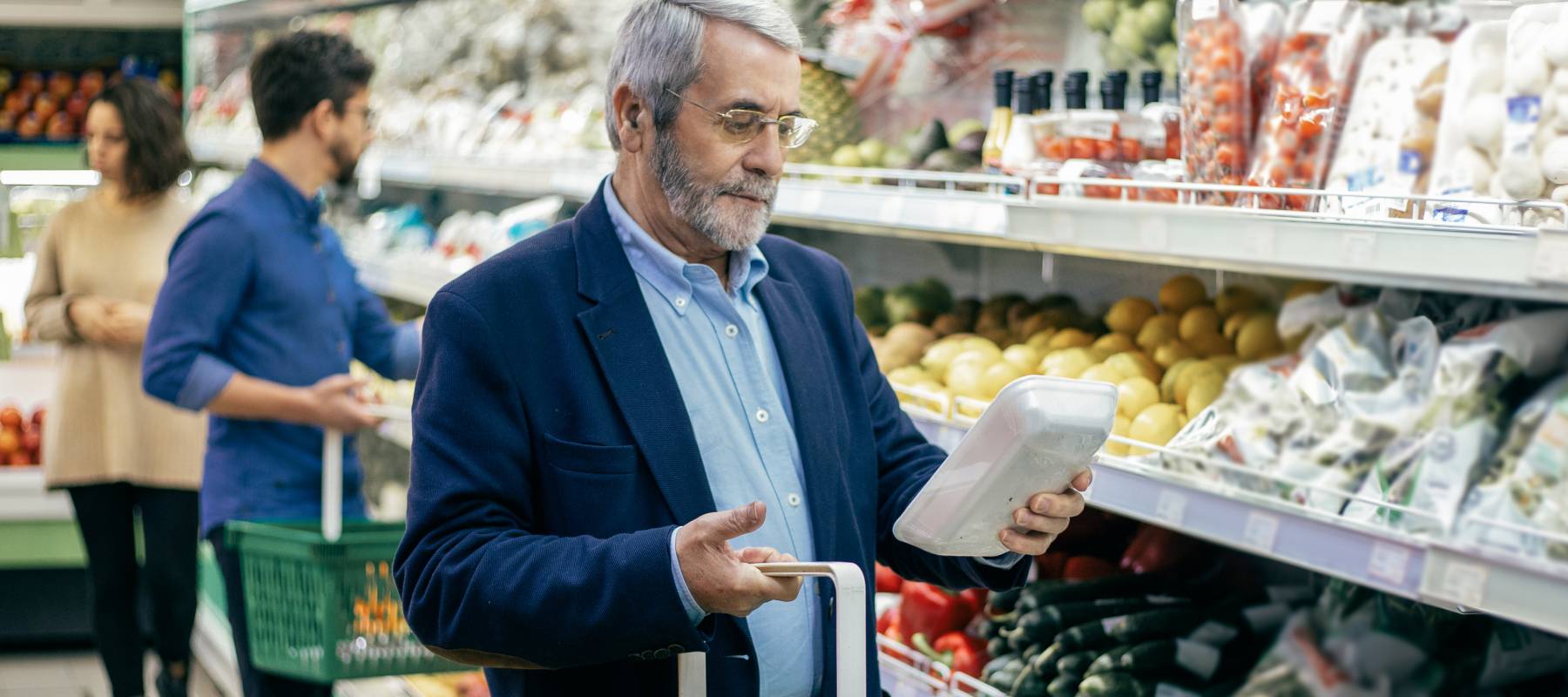Mature man choosing vegetables in supermarket.
