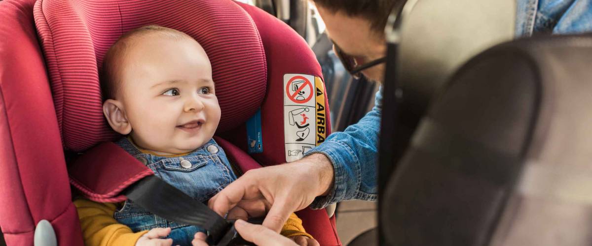 Father fasten his little baby in the car seat