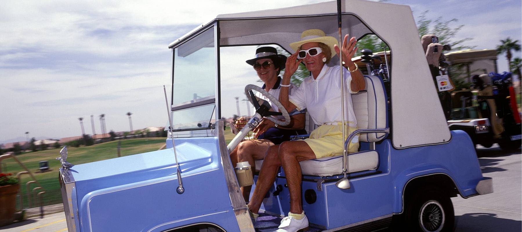 Two senior women in a gold cart.