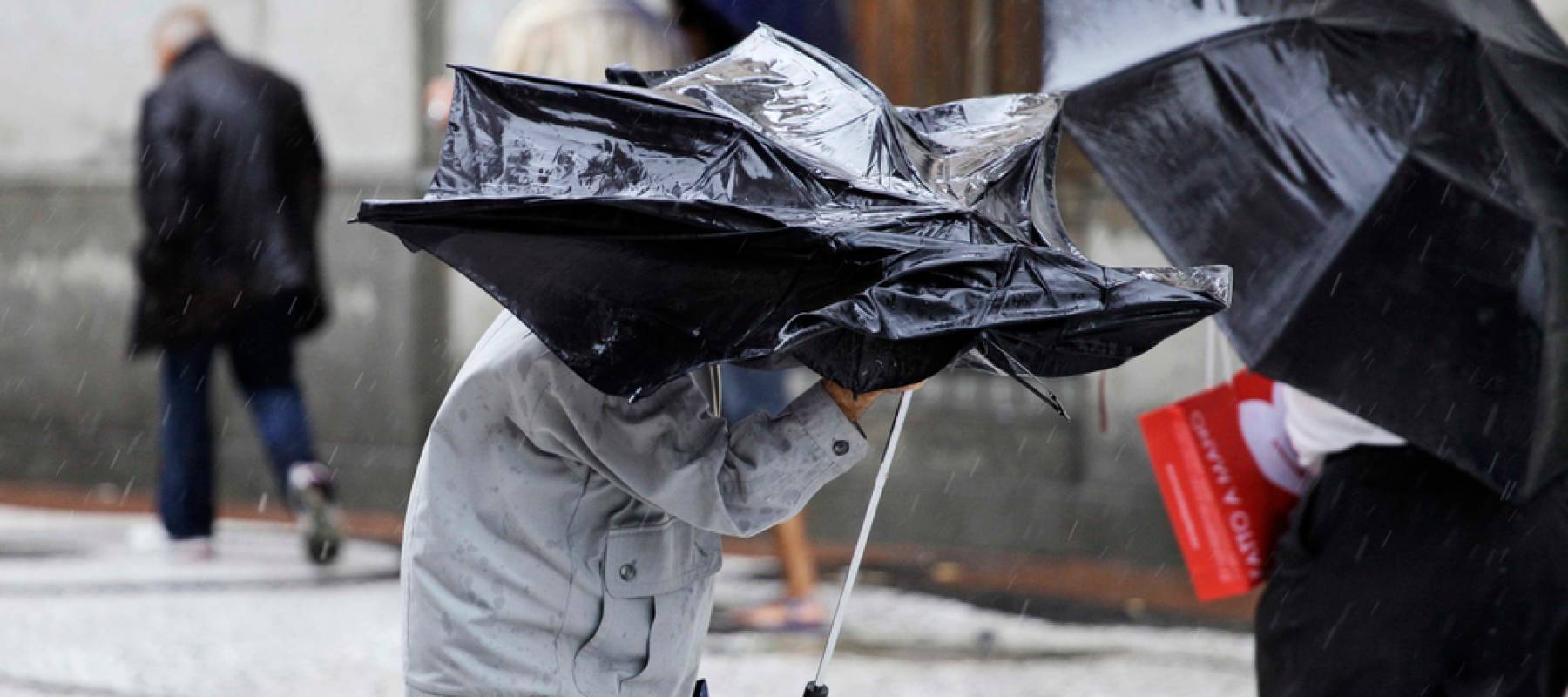 A elderly man use a umbrella to protect himself